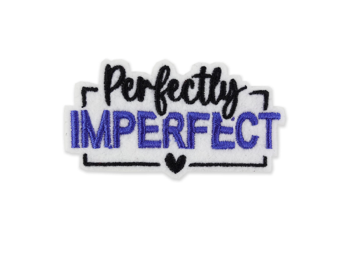 White and blue "Perfectly Imperfect" embroidered patch featuring blue block lettering for "IMPERFECT" and black script on a white felt background with a small black heart.