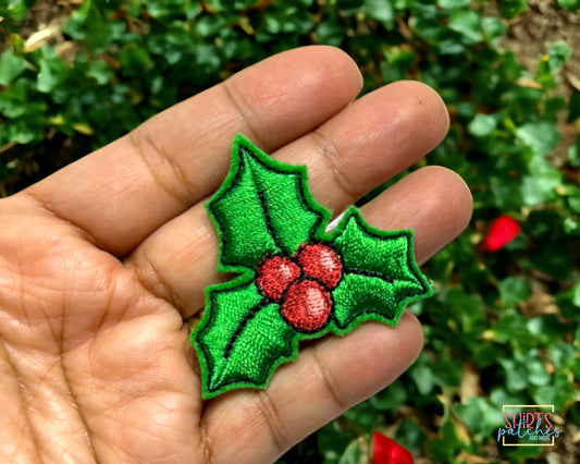 Hand holding the embroidered holly patch to show its size