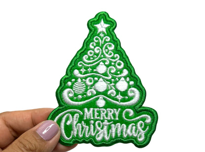 Close-up of the Christmas tree patch held between fingers showing stitch detail