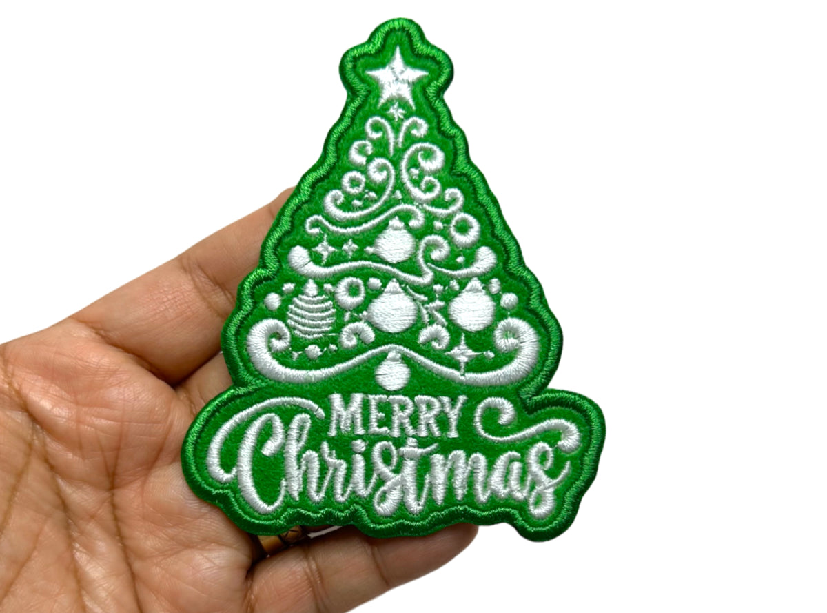 Christmas tree patch held in hand to show size - 3.1 by 4 inches
