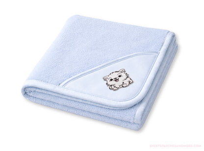 Folded light blue baby blanket with a  small patch of a White Pomeranian dog on a white background