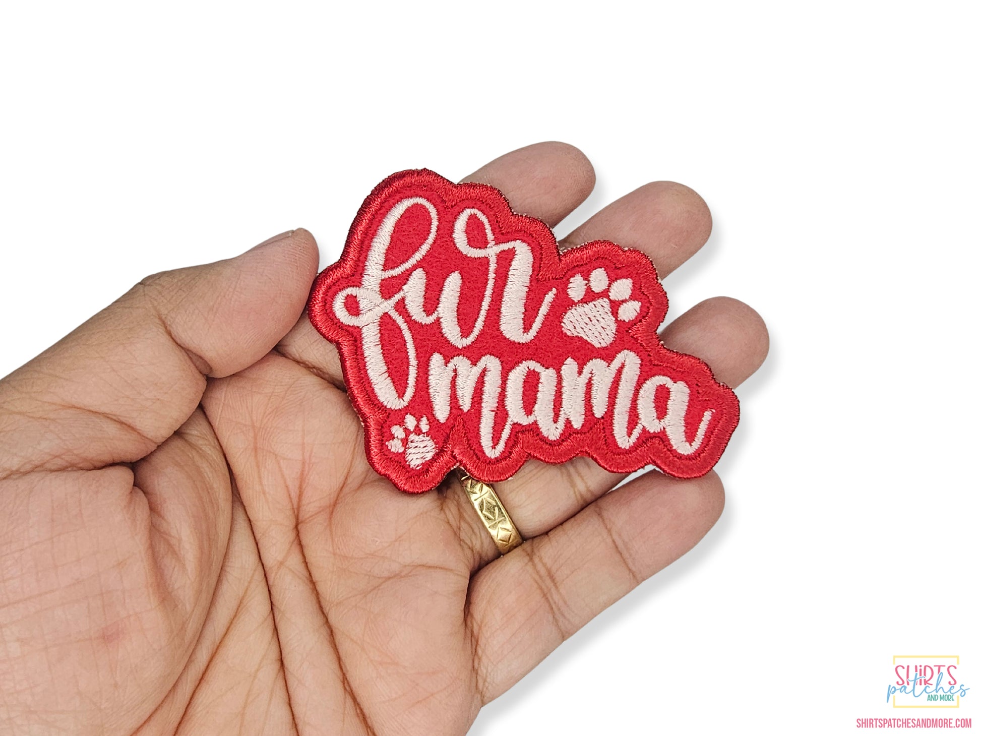 Custom red embroidered Fur Mama patch with white script lettering and paw print accents, held in a hand to show size.