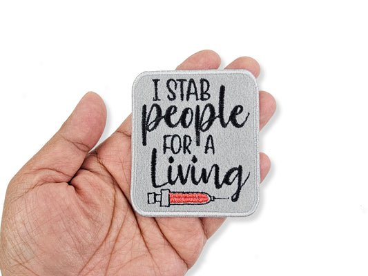 Patch with 'I stab people for a living' text held in a hand on a white background