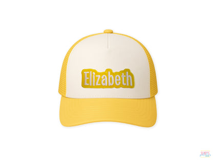 Yellow and white trucker cap mockup with the name 'Elizabeth' embroidered in yellow on a white patch, centered on the front. Custom name patch application example.