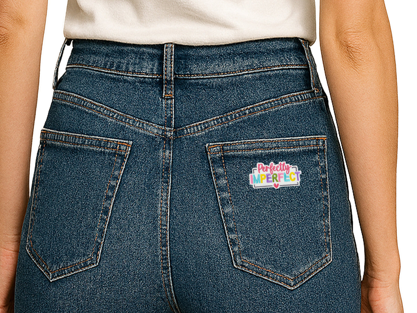 Back view of blue denim jeans featuring a "Perfectly Imperfect" colorful embroidered patch on the right back pocket, showing a creative way to customize clothing.