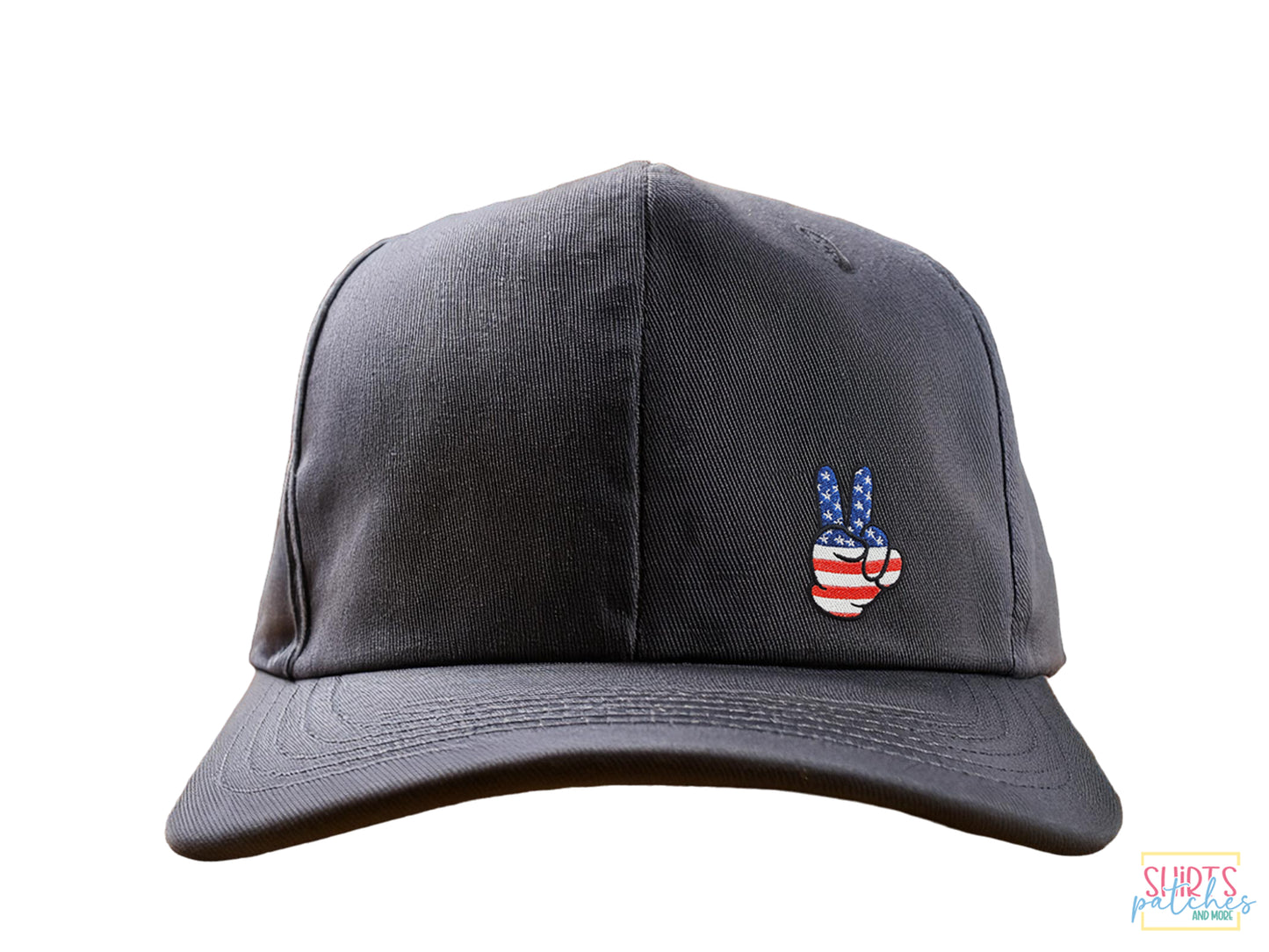 A gray baseball cap featuring a patriotic hand-embroidered peace sign patch with an American flag stars and stripes design on a white background.