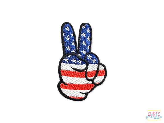 Hand-embroidered peace sign patch featuring a red, white, and blue American flag stars and stripes design on a white background.