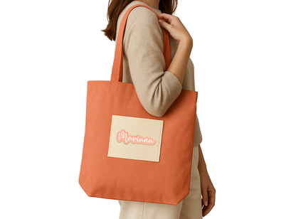 Mariana embroidered name patch applied to an orange tote bag being carried over the shoulder