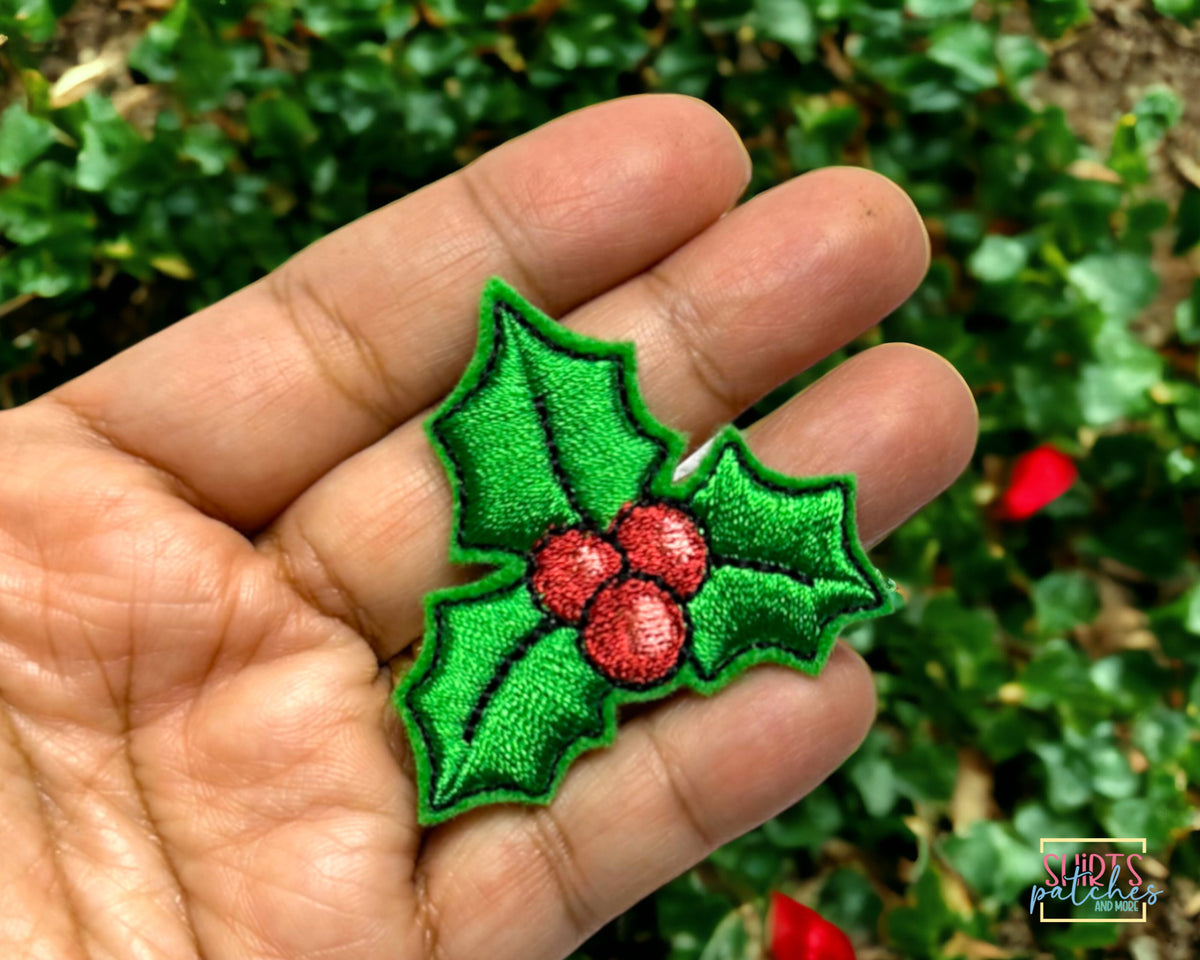 Hand holding the embroidered holly patch to show its size