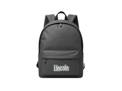 Mockup of a gray backpack with an embroidered 'Lincoln' custom name patch centered on the lower pocket, displayed on a white background.