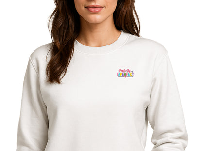 Perfectly Imperfect" colorful embroidered patch on a white long-sleeve sweatshirt, styled as a minimalist chest detail for a positive aesthetic.
