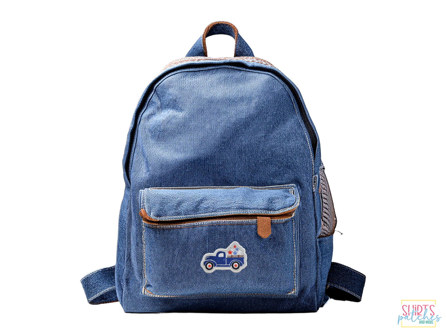 A blue denim backpack with a small front pocket featuring a blue patriotic vintage truck embroidered patch on a white background.