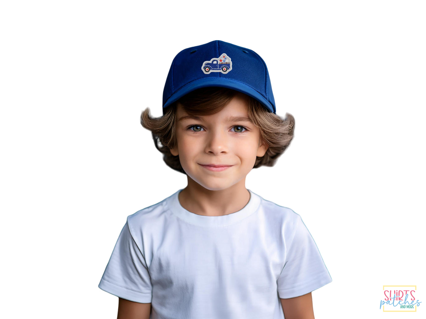 A young boy wearing a white t-shirt and a dark blue baseball cap featuring a blue patriotic vintage truck embroidered patch on a white background.