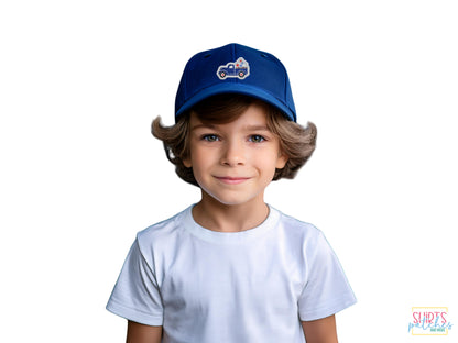 A young boy wearing a white t-shirt and a dark blue baseball cap featuring a blue patriotic vintage truck embroidered patch on a white background.