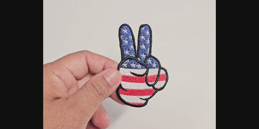 Video demonstration of a hand-embroidered peace sign patch featuring a patriotic red, white, and blue American flag design with stars and stripes.