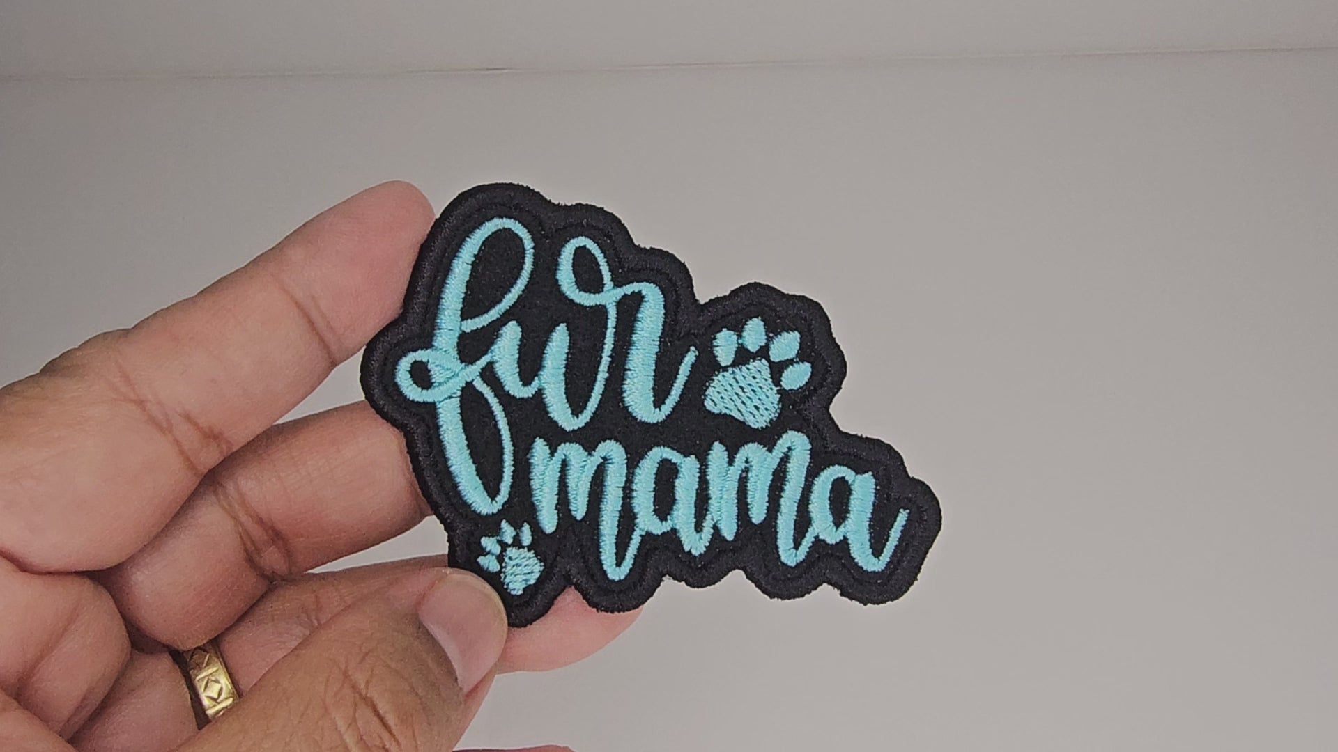Video showcasing a hand holding a Fur Mama iron-on patch to demonstrate its 2.8" W x 2.1" H size and premium embroidery quality.