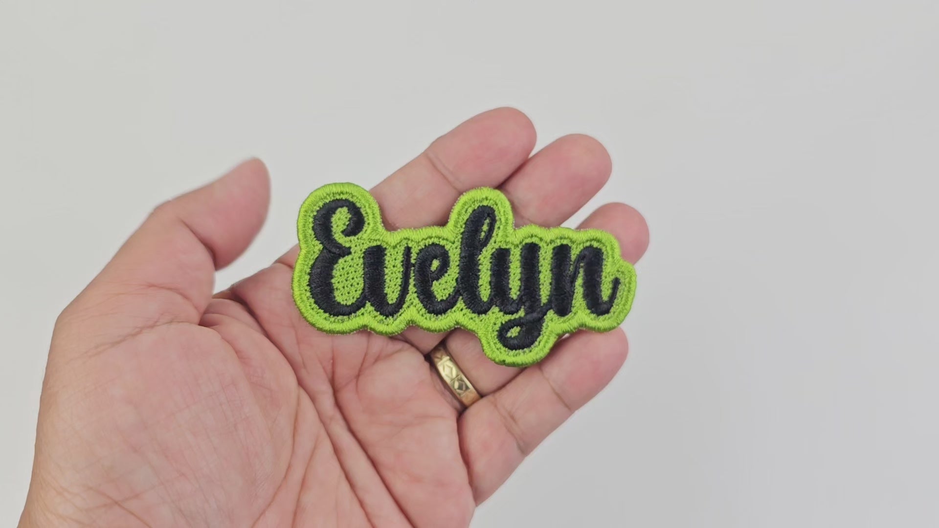 Short video demonstrating the finished quality, stitching, and texture of the personalized Evelyn name patch in black and lime green embroidery.