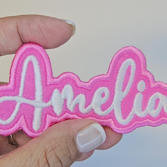 Video showing a close-up of the Amelia embroidered name patch held in hand and rotated to display stitching and details.