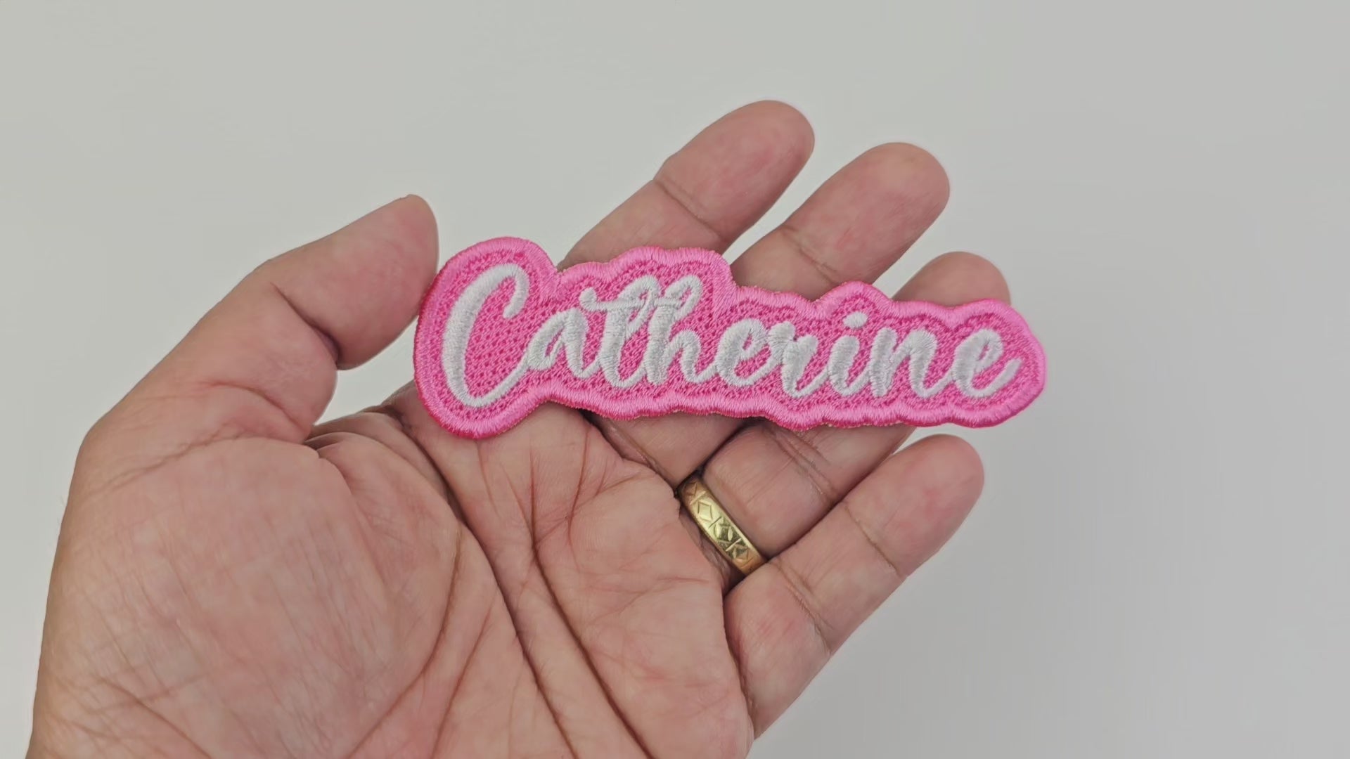 Video showing a close-up of the Catherine embroidered name patch held in hand and rotated to display stitching and details.
