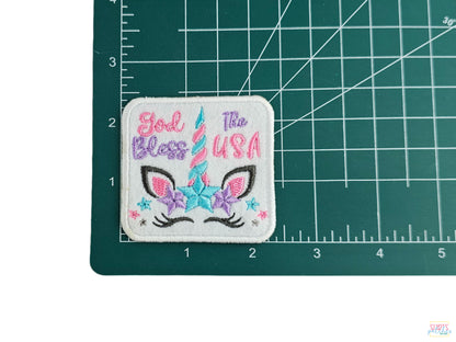 God Bless The USA unicorn embroidered patch shown on a measuring mat to demonstrate its 2.5-inch size.