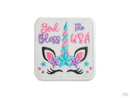 Embroidered pastel unicorn patch featuring 'God Bless The USA' text in purple and pink with a teal striped horn and sparkling stars.